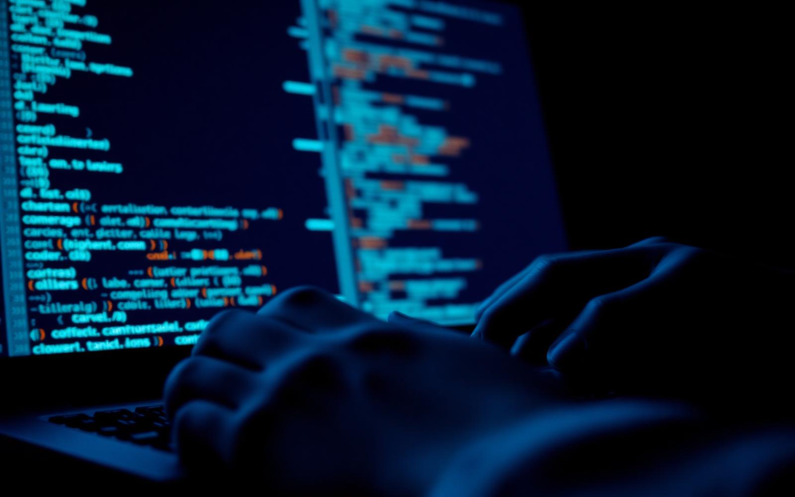 Close-up of a programmer's hands typing code on a laptop keyboard